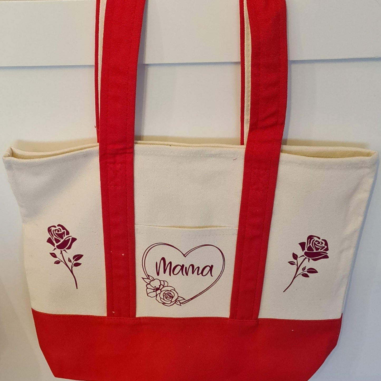 Tote bag with red handles and 'Mama' design on a white background