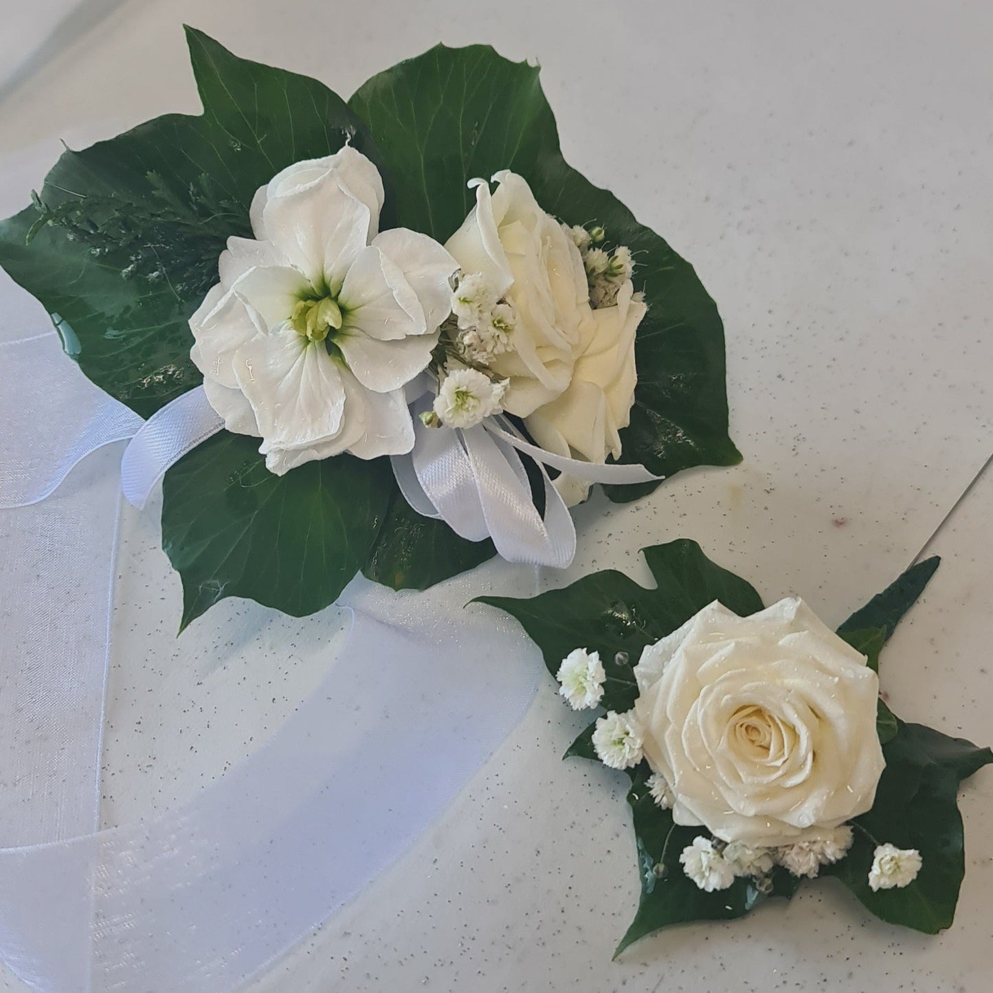 White floral corsages with green leaves
