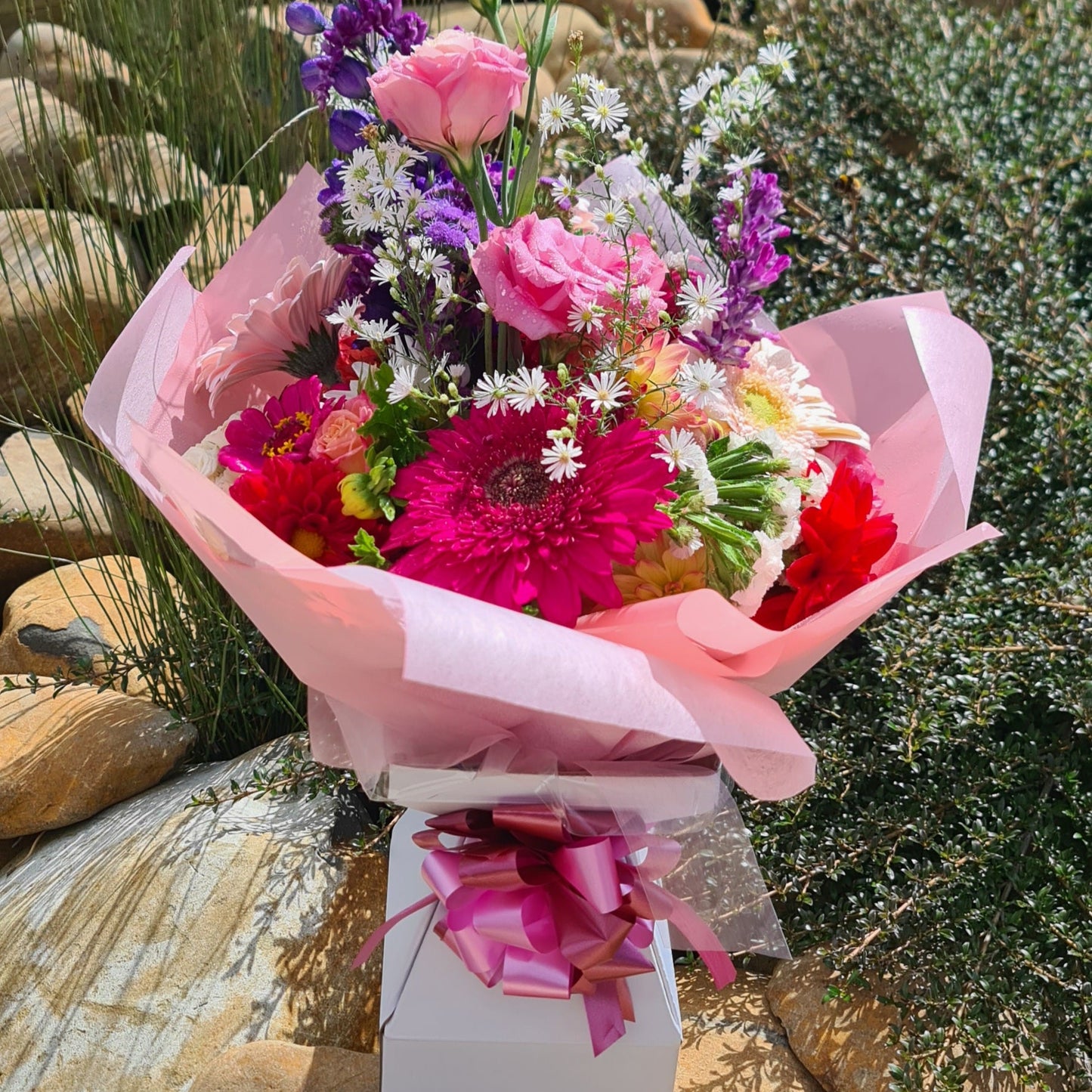 Bouquet of colorful flowers wrapped in pink paper in a Box Vas