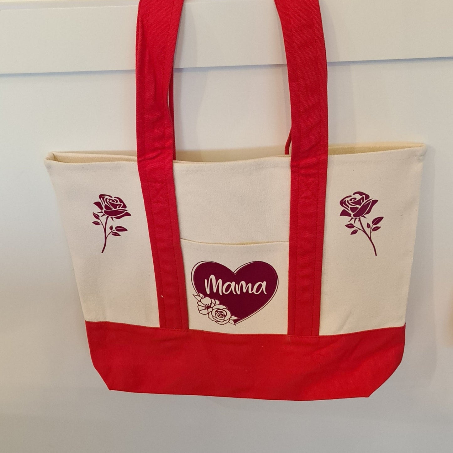 Tote bag with red handles and 'Mama' design on a white background